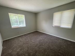 Louisville house for rent - an empty room with carpet and two windows