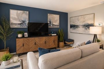 Baltimore townhouse for rent - A living room with a beige sofa, a wooden cabinet, and a painting on the wall.