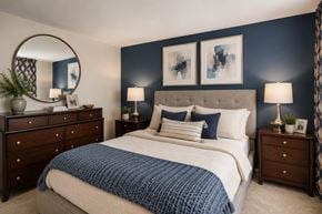 Baltimore townhouse for rent - A bedroom with a large bed, a round mirror, and a nightstand with a lamp.