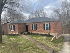 Louisville house for rent - A small brick house with a black door and windows.
