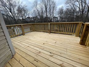 Louisville house for rent - A wooden deck with a railing and trees in the background.