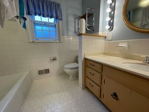 Louisville apartment for rent - A white tiled bathroom with a toilet, sink, and bathtub.