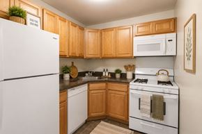 Dover apartment for rent - A kitchen with wooden cabinets and white appliances.