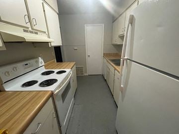 Louisville apartment for rent - A kitchen with white appliances and wooden countertops.
