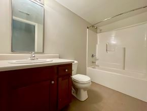 Louisville apartment for rent - A white toilet sits in a bathroom with a sink and mirror.
