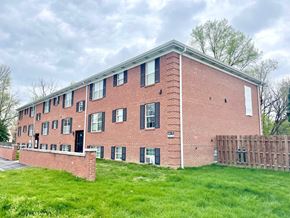 Louisville apartment for rent - A red brick building with black shutters and a white door.