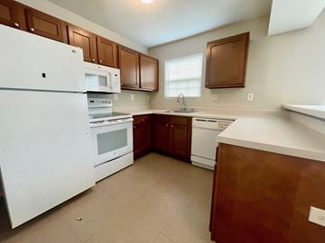Louisville apartment for rent - A kitchen with white appliances and brown cabinets.