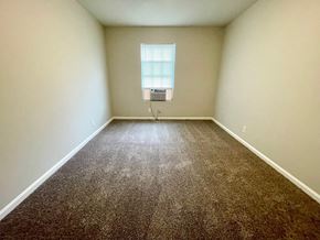 Louisville apartment for rent - A room with a brown carpet and a window with blinds.