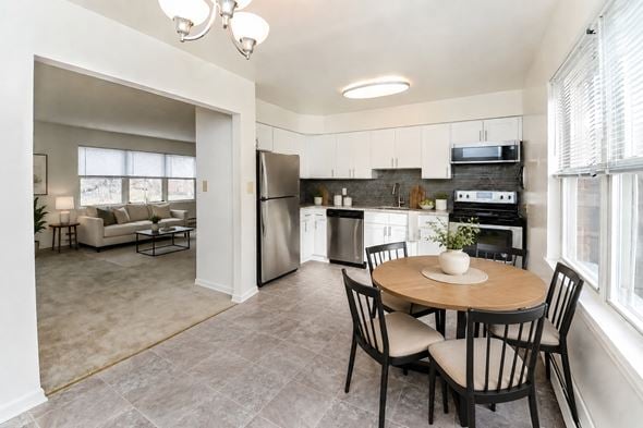 Eatontown apartment for rent - A kitchen with a table and chairs in the foreground and a living room in the background.