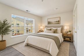 Franklin Lakes apartment for rent - A bedroom with a large bed and a window overlooking a building.