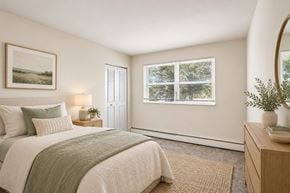 Bellmawr apartment for rent - A bedroom with a large bed and a window overlooking a tree-filled landscape.