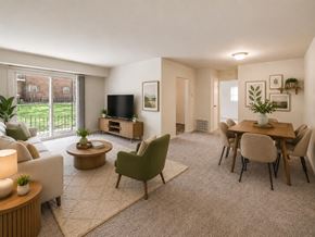 Freehold apartment for rent - A living room with a white sofa, a green chair, a wooden coffee table, and a television.