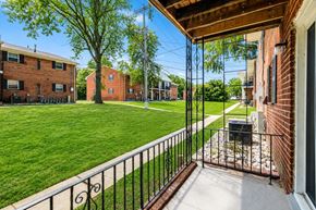 Freehold apartment for rent - A view from a balcony looking out at a green lawn and a brick building.