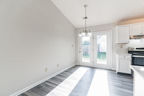 Louisville house for rent - an empty living room and kitchen with white cabinets and a door to a backyard