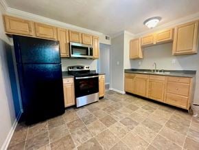 Louisville house for rent - a kitchen with wooden cabinets and a black refrigerator