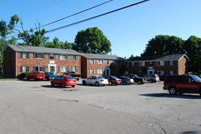 Crestwood apartment for rent - A parking lot with cars and a building in the background.
