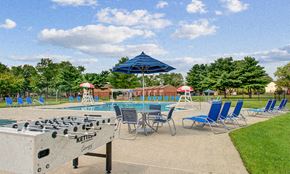 Eastampton apartment for rent - an outdoor pool with chairs and umbrellas and a shuffleboard