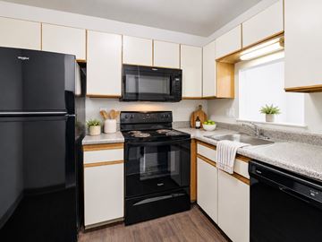 Clementon apartment for rent - A black refrigerator is on the left in a kitchen with white cabinets.