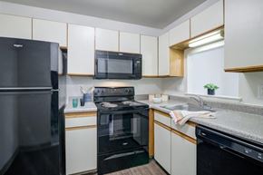 Clementon apartment for rent - a kitchen with black appliances and white cabinets