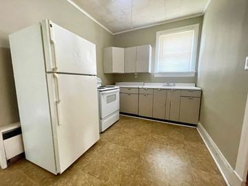 New Albany apartment for rent - A white refrigerator is in a kitchen with beige cabinets and a tiled floor.
