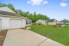 Havelock house for rent - A white house with a garage is surrounded by green grass and trees.
