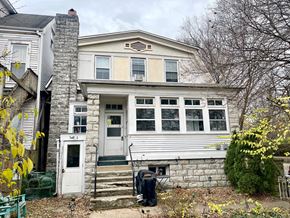 Louisville apartment for rent - A house with a white door and windows is surrounded by trees and bushes.