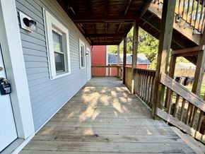 Louisville apartment for rent - A wooden deck with a white door and a red house in the background.
