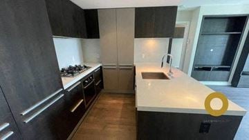 Vancouver house for rent - A modern kitchen with dark wood cabinets and a white countertop.