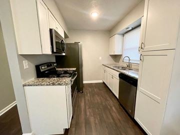 Louisville house for rent - an empty kitchen with white cabinets and stainless steel appliances