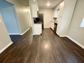 Louisville house for rent - an empty living room and kitchen with wood floors and white cabinets