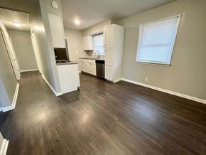 Louisville house for rent - an empty living room with wood floors and a kitchen