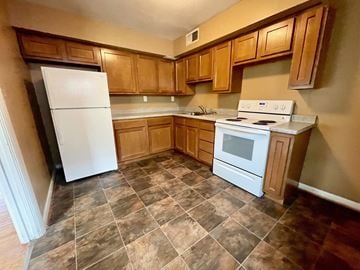 Louisville apartment for rent - A kitchen with a white fridge and stove top oven.