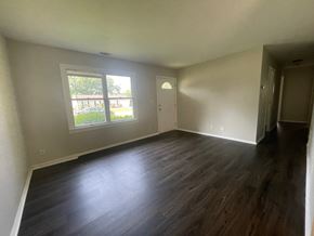 Louisville house for rent - A room with wooden floors and a window showing a view of a building and trees.