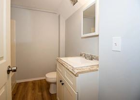 Akron apartment for rent - A white bathroom with a toilet, sink, and mirror.