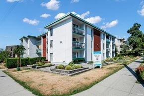North Vancouver apartment for rent - A white apartment building with a green roof and a sign in front.