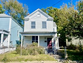 Louisville house for rent - A white house with a red door is surrounded by a fence and greenery.