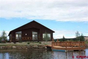 Pagosa Springs house for rent - A house with a deck is situated by a body of water.
