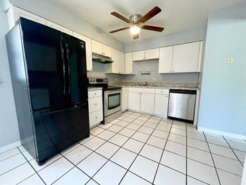 Louisville house for rent - a kitchen with white cabinets and a black refrigerator