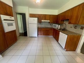Louisville house for rent - an empty kitchen with white appliances and wooden cabinets