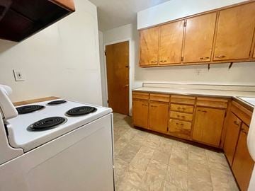 Louisville apartment for rent - A kitchen with a white stove top oven and wooden cabinets.