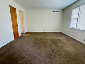 Louisville apartment for rent - A room with brown carpet and a wooden door.