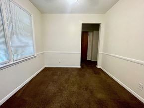 Louisville apartment for rent - A room with brown carpet and a door at the end.