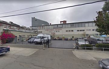 Oakland apartment for rent - The image shows a street view of Ford Street Studios with a grey building and a black van parked in front.