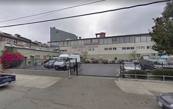 Oakland apartment for rent - The image shows a street view of Ford Street Studios with a grey building and a black van parked in front.