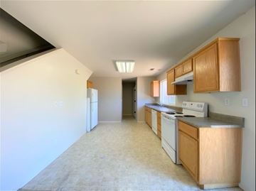 Merced house for rent - a kitchen with white appliances and wooden cabinets
