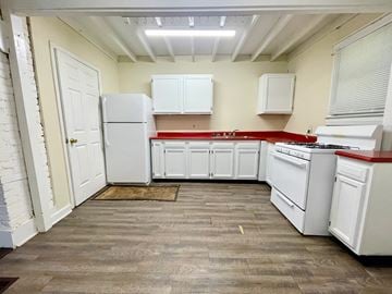 Louisville house for rent - A kitchen with white appliances and wooden floors.