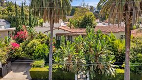 Los Angeles apartment for rent - A house with a red tile roof is surrounded by green plants and trees.