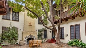 Los Angeles apartment for rent - A patio with a table and chairs is surrounded by a tree and a building.