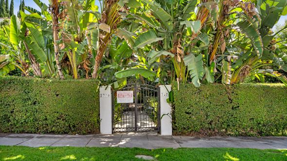 Los Angeles apartment for rent - A gate with a sign that says "No Trespassing" is surrounded by greenery.