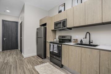 Rochester Hills apartment for rent - A kitchen with a black refrigerator and wooden cabinets.